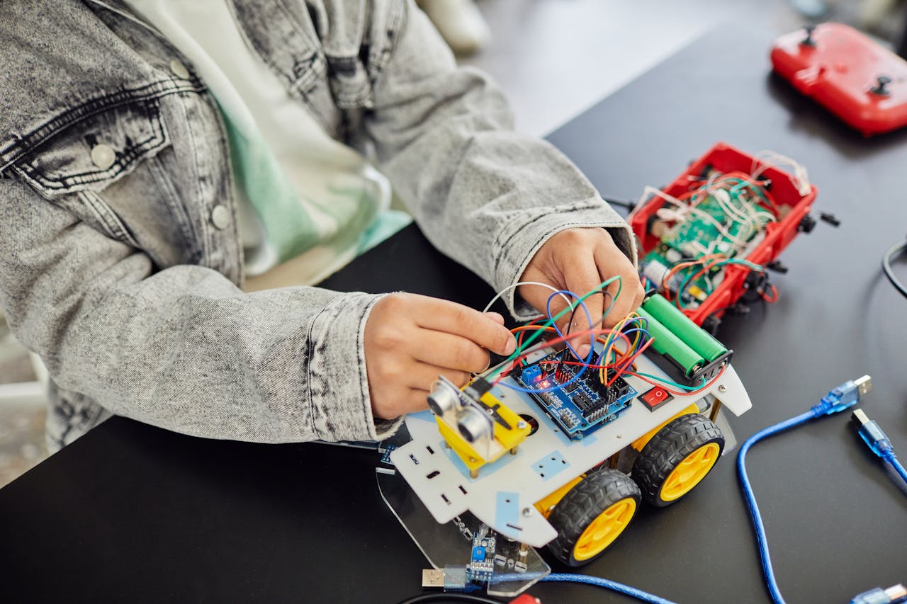 Services Young student assembling a toy car with electronic components, focusing on STEM education.