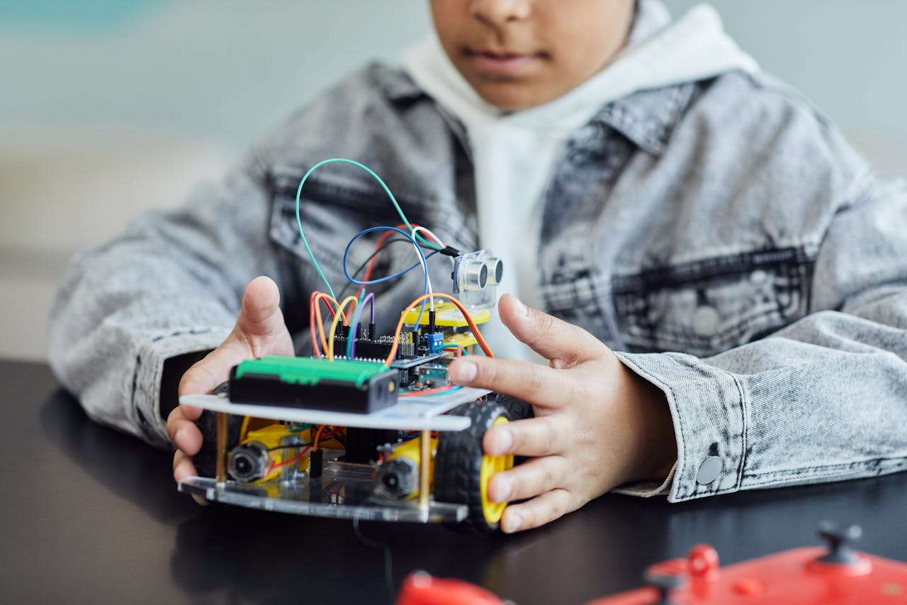 A child working on a DIY robotics project with wires and wheels, showcasing innovation and creativity.