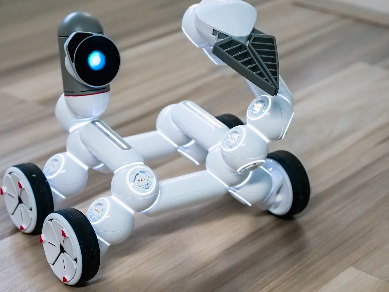 Close-up of a flexible modular robot with wheels on a wooden floor, showcasing modern robotics technology.